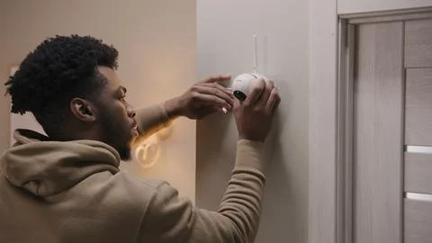 Man puts security camera on wall fastening Stock Photos