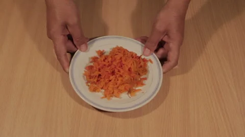 Man puts shredded carrots on the table Stock Footage 68502949