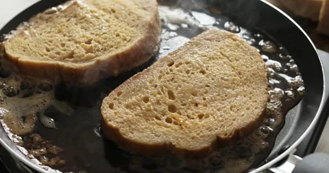 A man puts slices of bread soaked in beaten egg on a hot frying pan. Stock Footage 250105377
