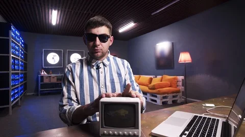 Man puts small old grey TV on desk then throws it behind his back . Stock Footage 106650107