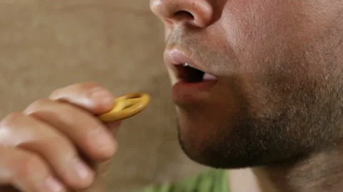 The man puts a small pretzel in his mouth and chews it. Close-up, real time, ind Stock Footage 93208361