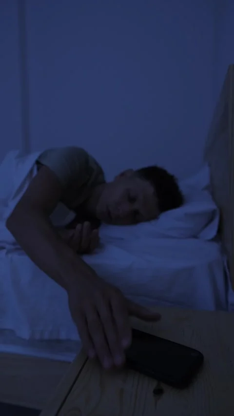 Man puts smartphone away at bedtime and goes to sleep, reducing screen time for Stock Footage 346244772