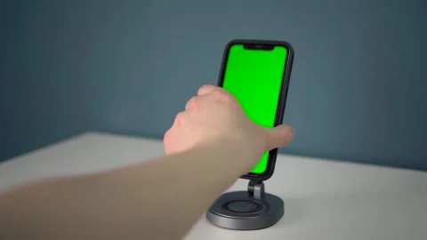 A man puts a smartphone with a green screen on a magnetic stand with wireless Stock Footage 314465378