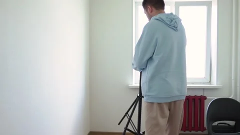 A man puts a stand, sets up, adjusts a light source for filming Stock Footage 154646591