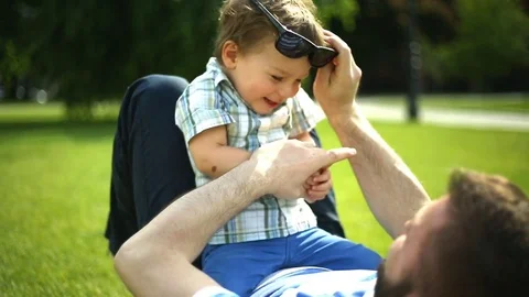 Man puts sunglasses on his son's face and have fun in the park Stock Footage
