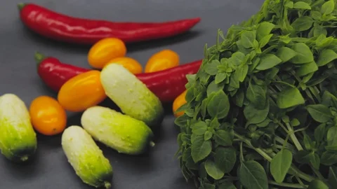 A man puts on the table basil, cherry tomatoes, chili peppers, mini cucumbers Stock-Footage 125653674
