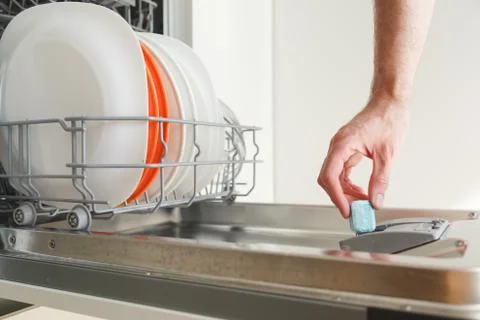 Man puts a tablet in the dishwasher Stock Photos