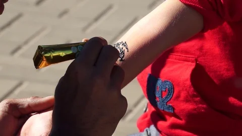 A man puts a temporary tattoo, draws on the body with henna. Video stock 100601021