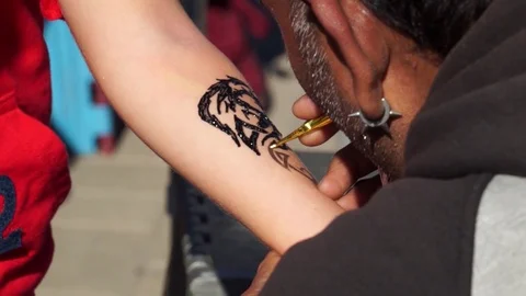 A man puts a temporary tattoo, draws on the body with henna. Stock Footage 100601031