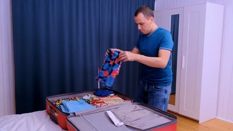 A man puts things in a suitcase for traveling Video stock 123712583
