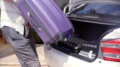 The man puts the third big heavy suitcase with things in the trunk of the car Stock Footage 87448648