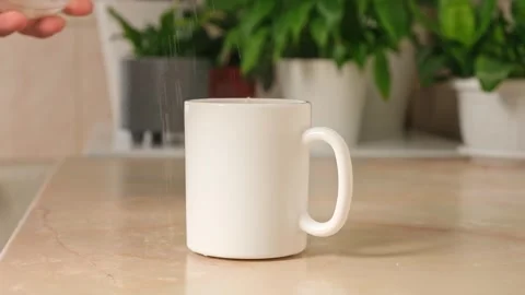 Man puts three teaspoons of sugar in cup with a tea bag and hot water to make Stock Footage 244803785