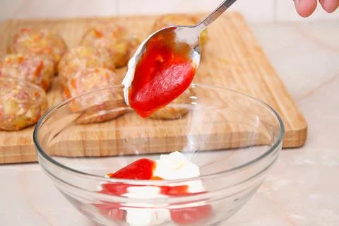 A man puts tomato paste, ketchup for pouring to cook lazy cabbage rolls in slow Stock Photos