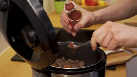 The man puts tomato paste into the slow cooker Stock Footage 129051286