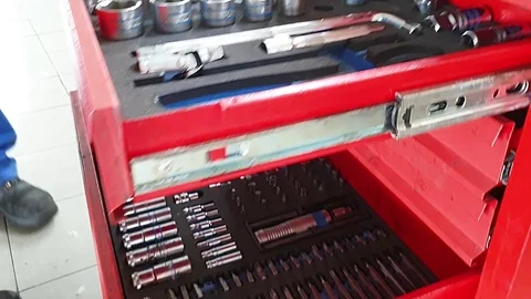 Man puts the tools into the holes in tool box, red iron chest in car workshop Vídeo Stock 122394088