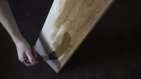 A man puts on a tree decorative coating darkening wood Video stock 119392384