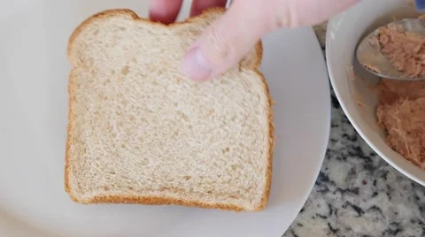 A man puts tuna fish on bread for a sandwich Video stock 57877987