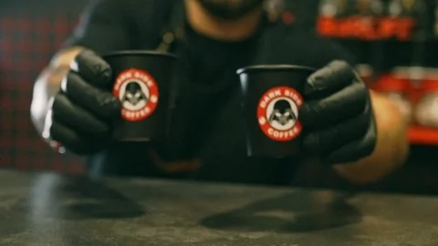 Man puts two espresso shots in paper cups on bar table Stockbeeldmateriaal 115699373