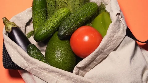 A man puts vegetables in a cotton bag on an isolated colored background Stock Footage 125770943