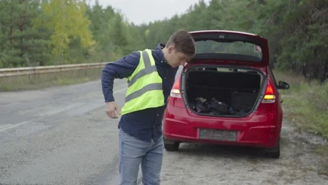 A man puts on a vest when a car breaks down on the road. Stock Footage 221243767