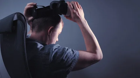 A man puts on virtual reality glasses while sitting on a chair. 4k video Stock Footage 115089460