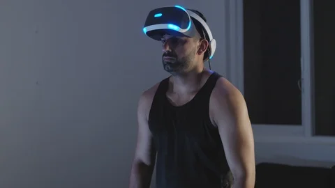 Man Puts Virtual Reality Goggles on, Ready to Play Video Game, Raises Gun Stock Footage 108880497