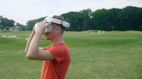A man puts a VR headset on his head in a park and looks around Stock Footage 112804821