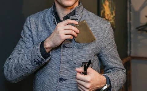 A man puts a wallet in the breast pocket of his jacket Stock Photos