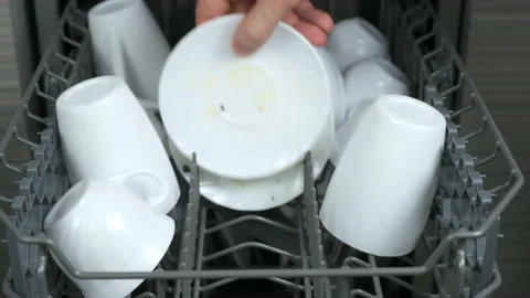 Man puts white dirty dishes in upper basket of dishwasher on the kitchen. Stock Footage 233095667