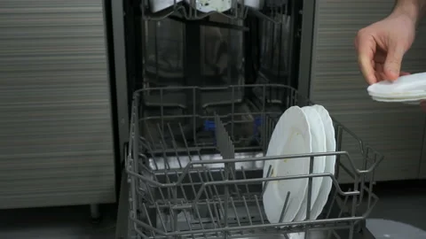 Man puts white dirty dishes in down basket of dishwasher on the kitchen. Stock Footage 237613437