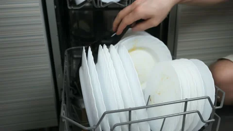 Man puts white dirty dishes in upper basket of dishwasher on the kitchen. Video stock 237613620