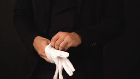 Man puts on white gloves on a dark background. Strong hands of a man. Long time. Video stock 125456225