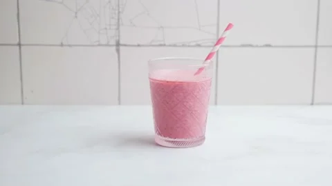 Man puts on white table two glasses of pink strawberry milkshake or smoothie Stock Footage 155943654