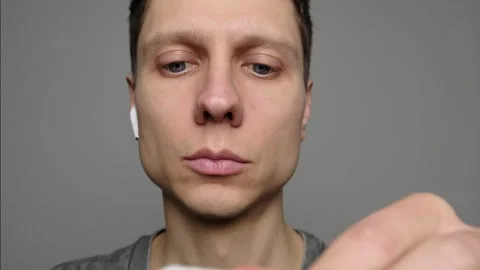 Man puts wireless Bluetooth earbuds into his ears Stock Footage 297462034