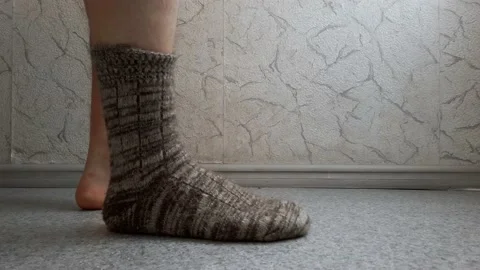 The man puts on woolen socks on his bare feet. Stock Footage 147887412