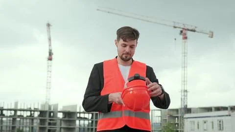Man puts on work clothes, checking process at construction site Stock Photos