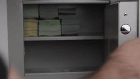 Man Putting Black Handgun into Open Safe Box with Money Stacks Stock Footage 340405406