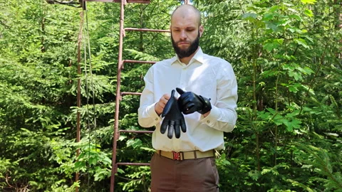 Man putting on black leather gloves near base of tower ladder Stock Footage 338115267