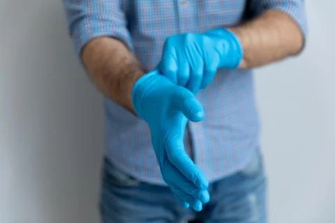 Man putting on blue latex rubber gloves for household work Stock Photos