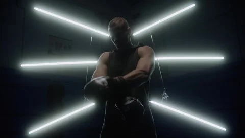 Man putting on boxing gloves getting ready for fight with light behind him Stock Footage 315563971