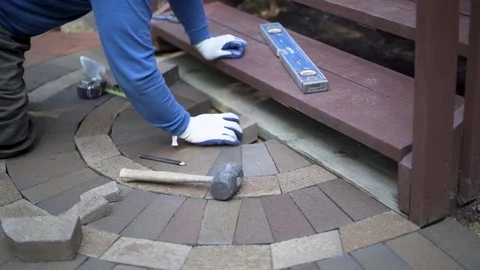 Man putting bricks in place for a decorative two tone paver pattern in front a Stock Footage 82012185