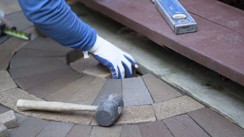 Man putting bricks in place for a decorative two tone paver pattern in front a Stock Footage 82089995