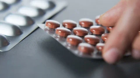 Man Putting Brown Tablets on a Table Stock Footage 69215475