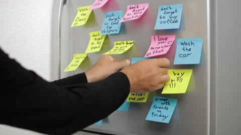Man Putting, Checking and Removing Colorful Sticky Notes With Appointments .. Stockbeeldmateriaal 289400784