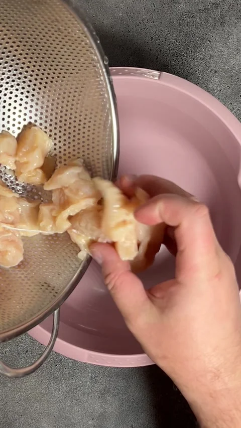Man putting chopped raw chicken pieces from colander to pink bowl Video stock 300652395