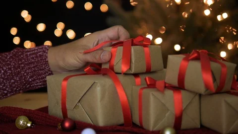 Man putting Christmas gift boxes at home with bokeh lights background Stock Footage 94486521