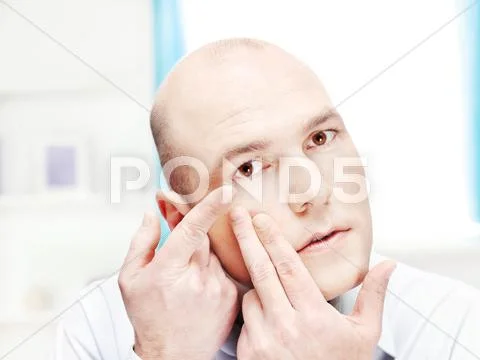 Man putting contact lens in eye Stock Photos