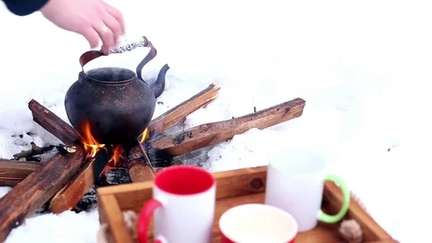 Man putting copper kettle on the open fire in winter snow Stock Footage 72706200