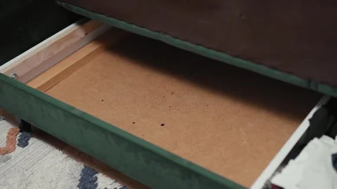 Man putting cotton bedding into under the couch storage place. Small space conce Stock Footage 319334755