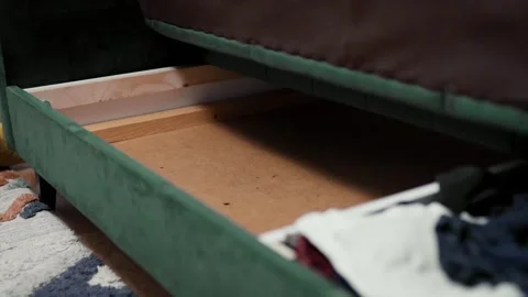 Man putting cotton bedding into under the couch storage place. Small space conce Stock Footage 319334774